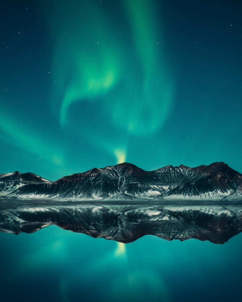 Iceland's northern lights over a lake and mountains.