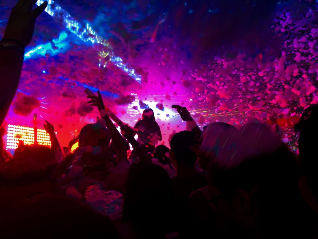 People dancing in pink and blue lights at a music festival or concert. 