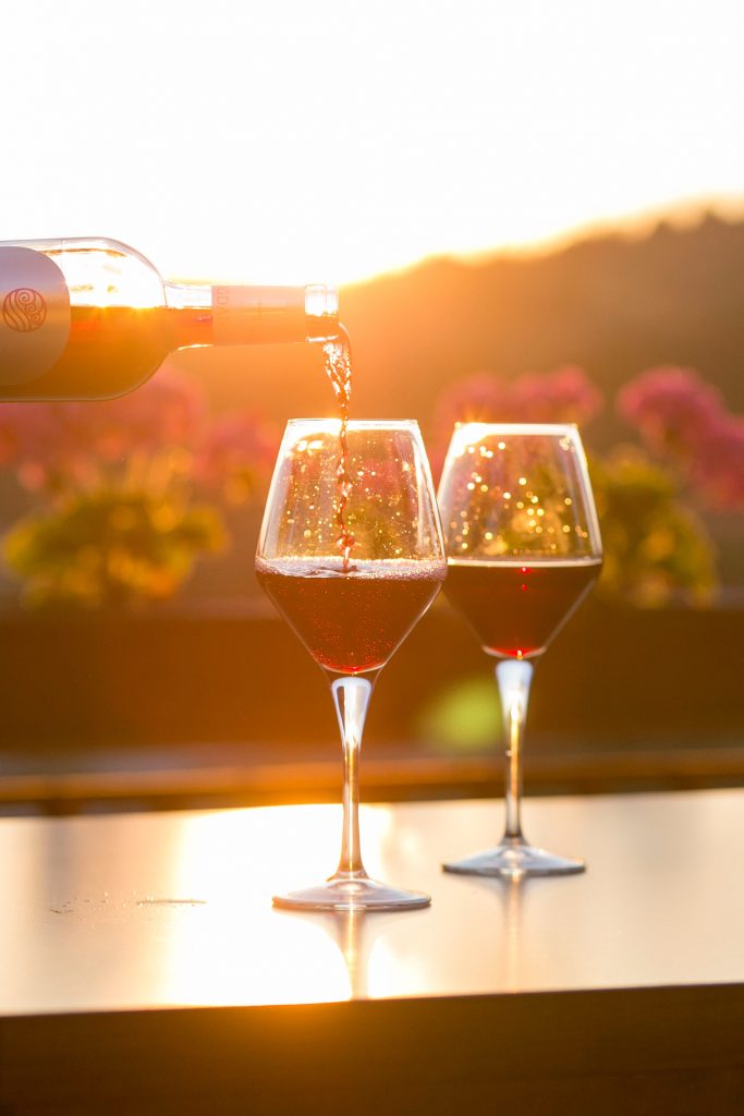 Picture of wine poured in front of a sunset. 