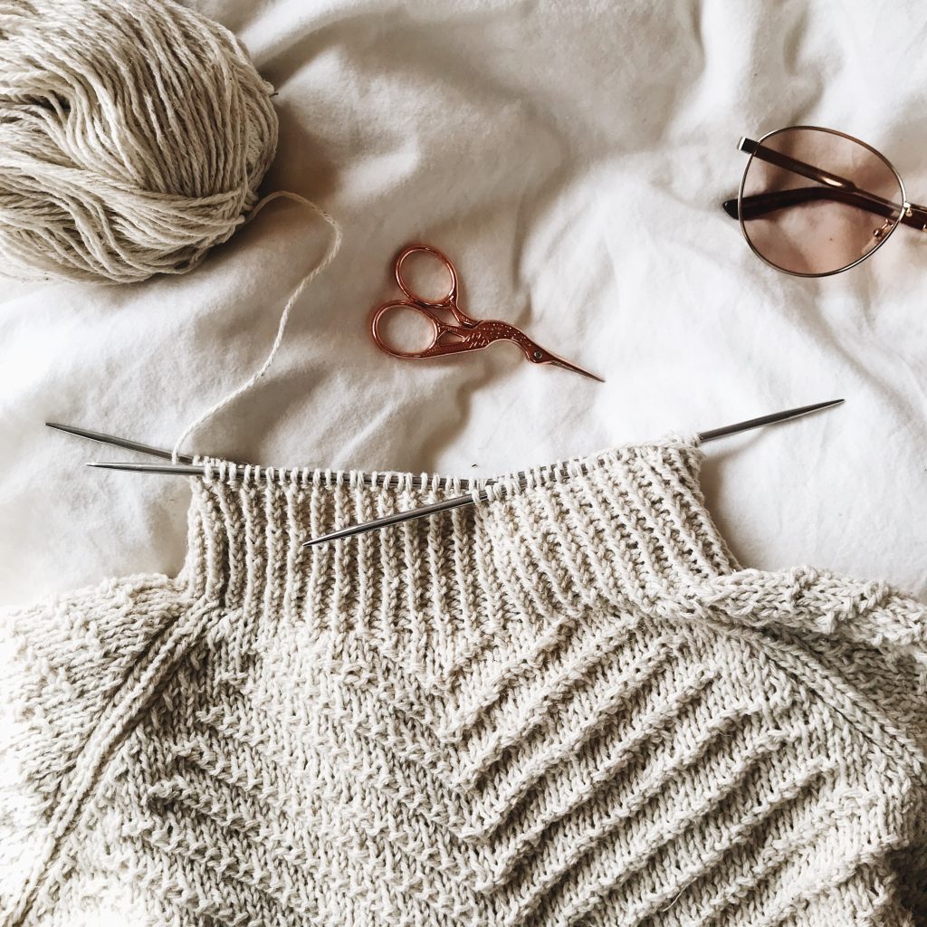 A knit wool sweater with scissors and sunglasses. 