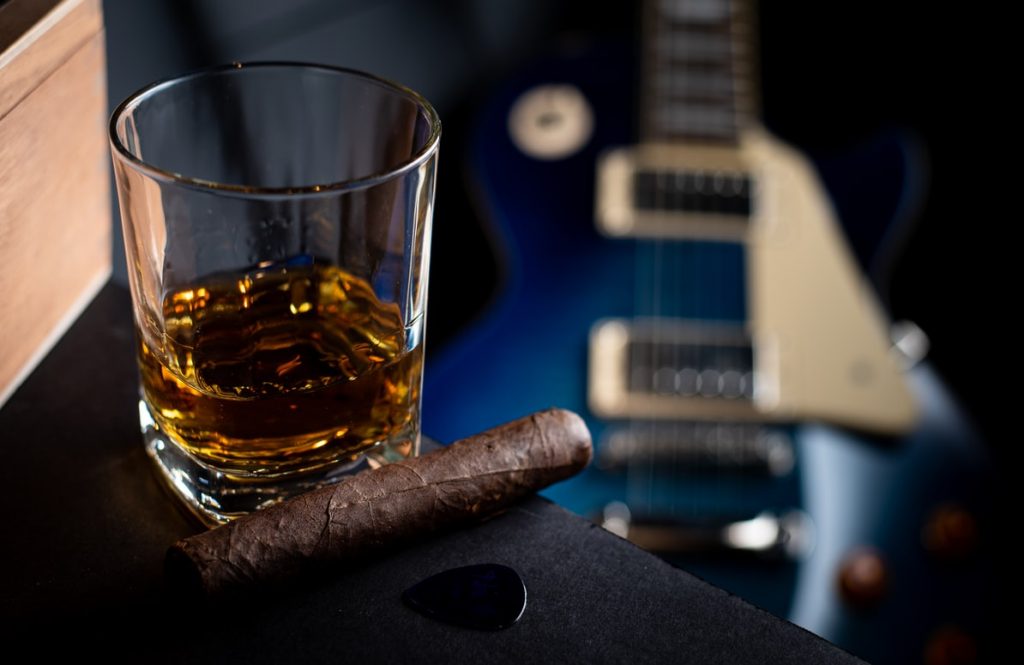 Cigar, whiskey and a guitar in the background.