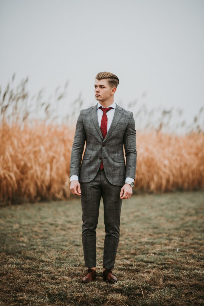 A man wearing a plaid suit in a field. 