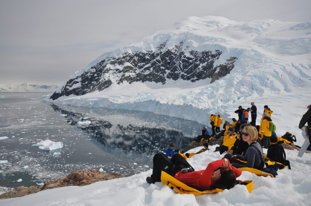 People siting on the snow in Antarctica. 