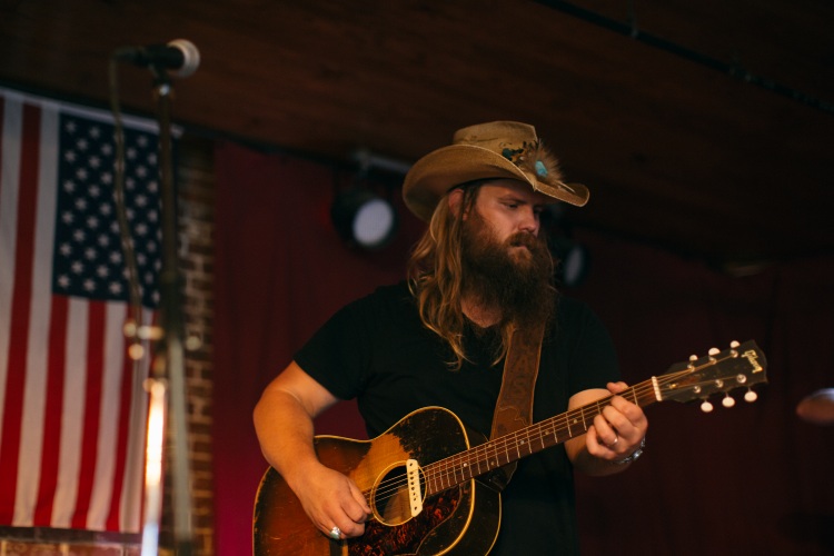 Chris Stapleton, who took home three Grammys, plays the guitar in front of an America flag. 