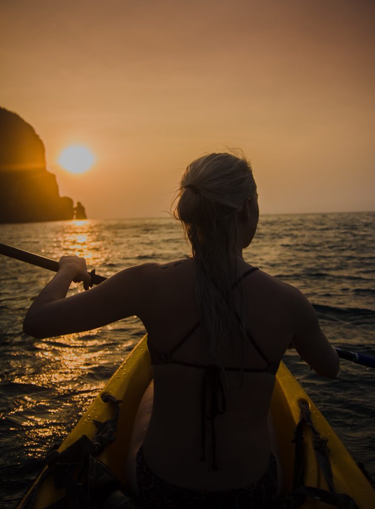 A woman kayaking at sunset in Thailand's south. 