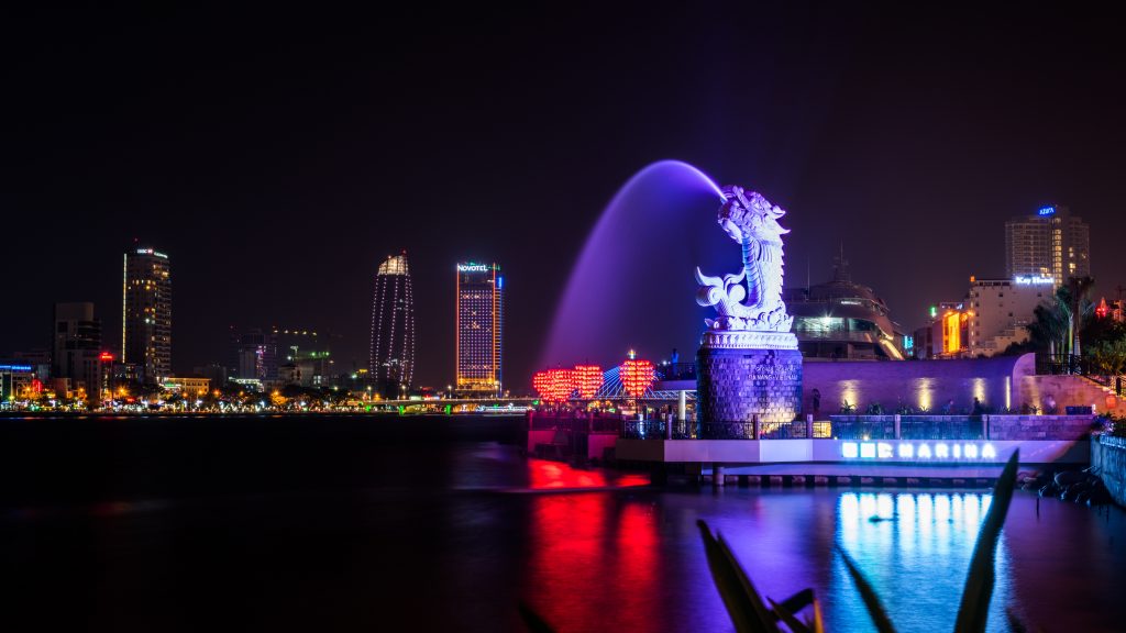 Da Nang in Central Vietnam. A dragon fountain spraying water into the river with skyscrappers in the background. 