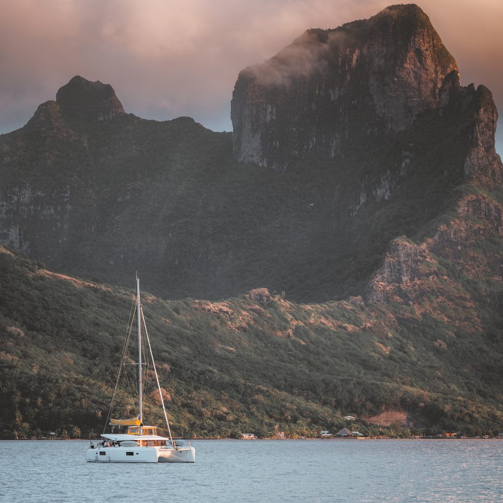A sail boat on the water in front of a mountain in Bora Bora. 