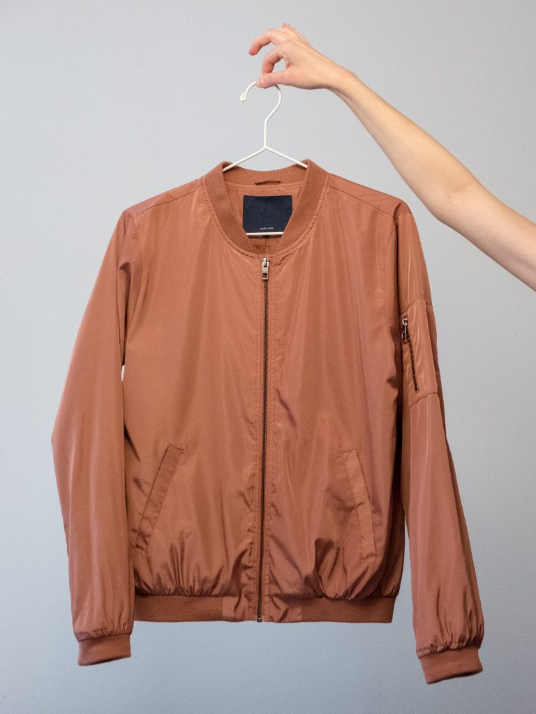 Some clothes need nylon or polyester for waterproofing. A person holding a synthetic fibre jacket. 